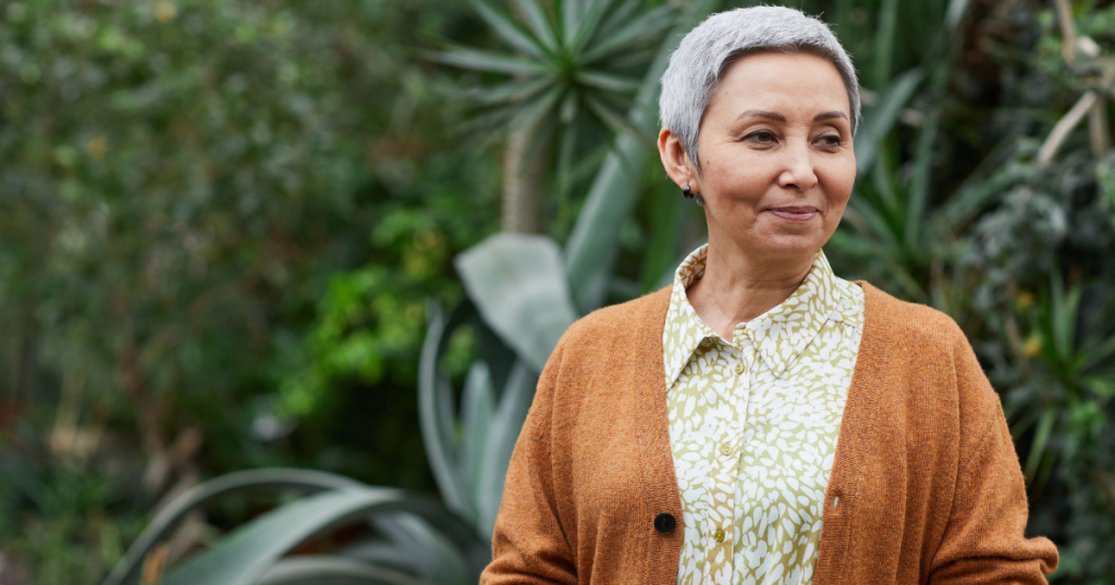 an older woman in an orange sweater looks pensively