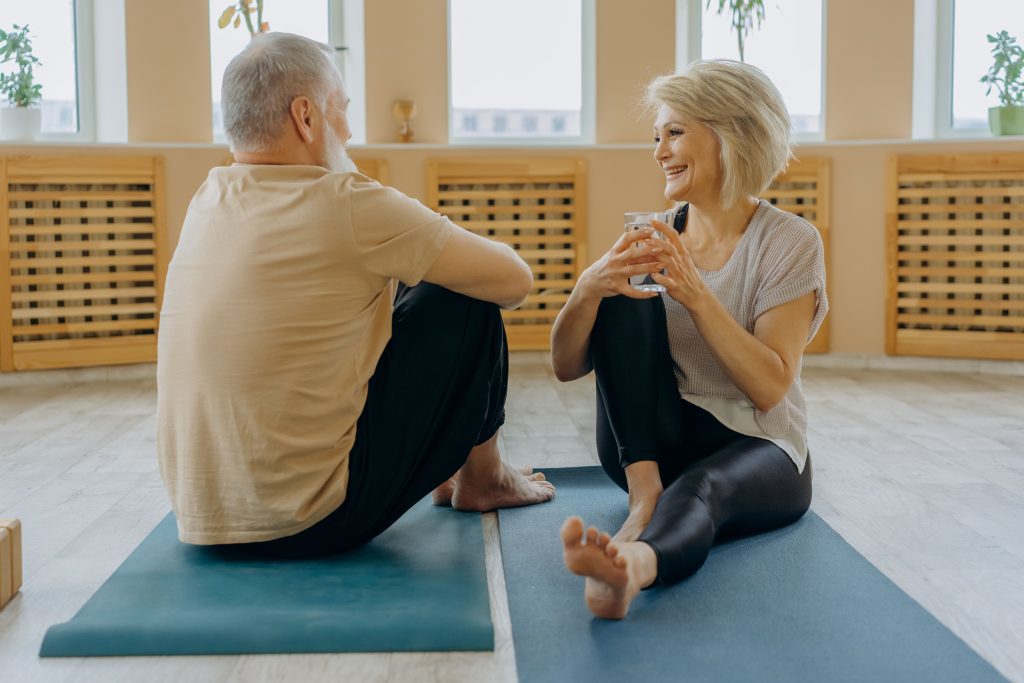 two seniors sit on yoga mat
